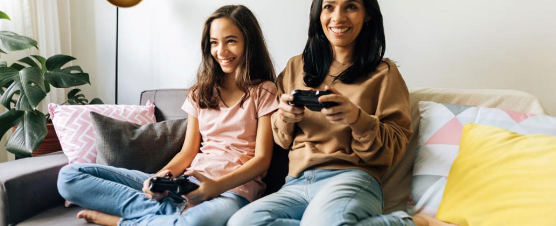 mother and daughter playing video games on couch