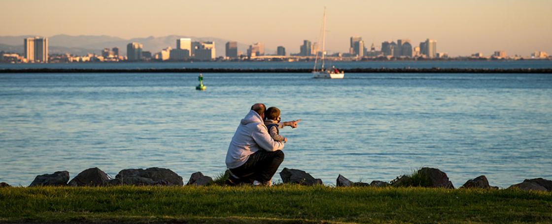 An adult and child looking onto a shoreline.