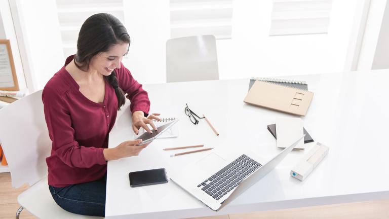Woman using work related devices at workstation 