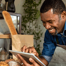 Cafe worker smiling and using an ipad.