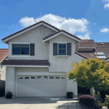 Facade of a two story house in Fremont with a driveway and surrounding trees and foliage.