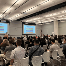 A group of people seated while listening to a presentation hosted by BayREN, displaying PowerPoint slides for municipal staff.