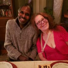couple smiling at camera, with one person putting head on shoulder of the other person.